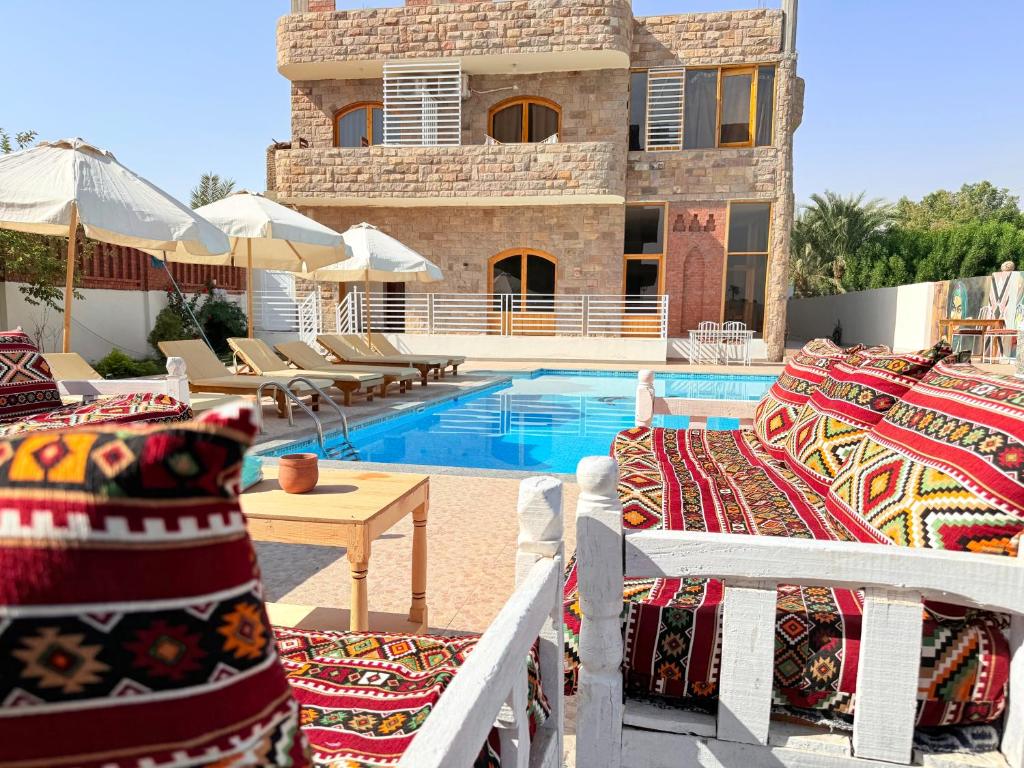 een resort met een zwembad en stoelen en een gebouw bij Citadel Luxor in Luxor