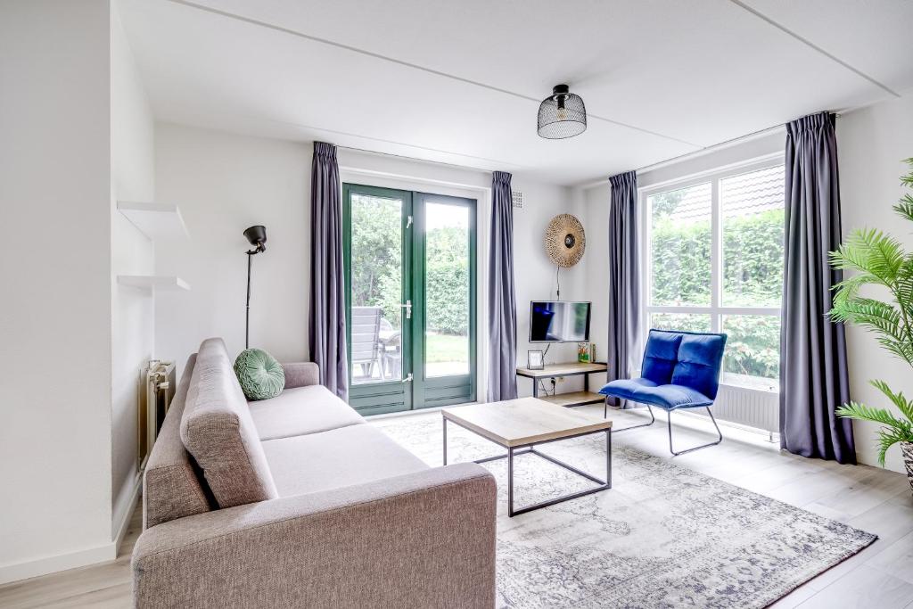 a living room with a white couch and a blue chair at 5-Person Forest 271 Bungalow in Ewijk
