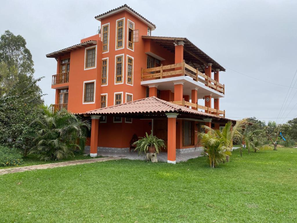 a large orange building with a green yard at La Casona - Hospedaje Campestre in El Carmen