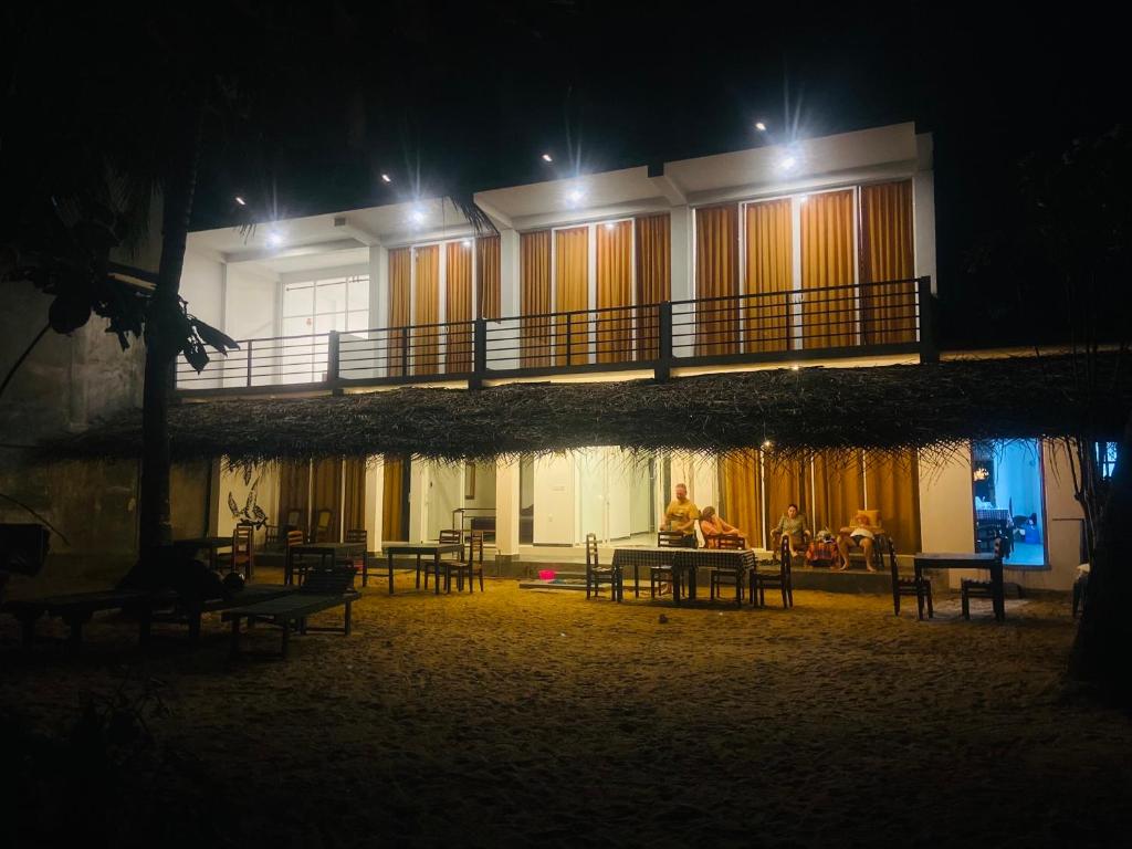 a man sitting at a table in front of a building at night at Sunray Beach House in Tangalle