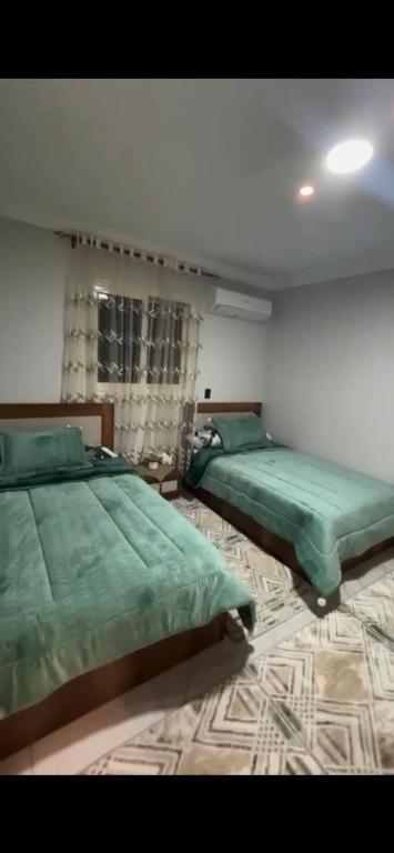 two beds in a bedroom with green sheets at شقة خاصة in Cairo