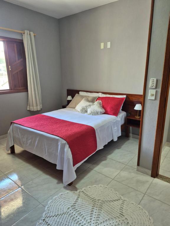 een slaapkamer met een bed met rode en witte kussens bij CASA 97 completa! Horário Flexível! in Santa Teresa