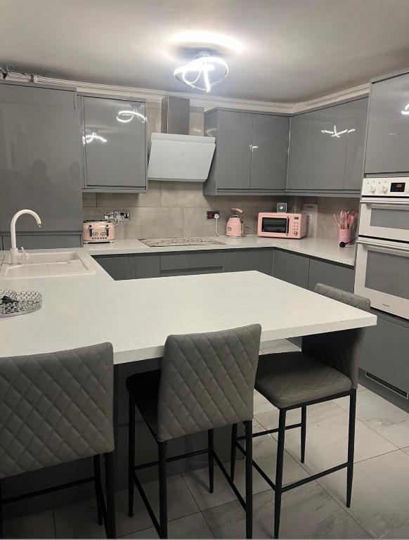 a kitchen with a white counter and chairs in it at Pats Place in Liverpool