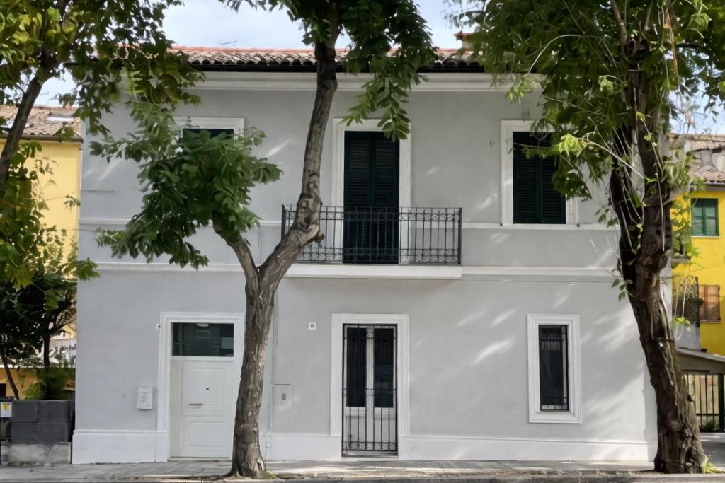 een wit huis met twee bomen ervoor bij La Casa Sul Viale in Iesi