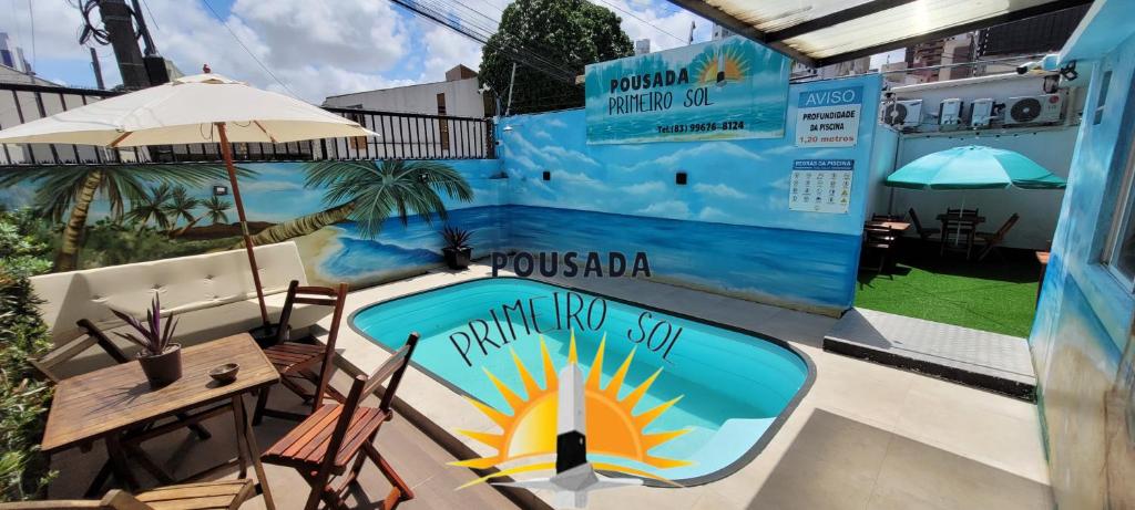 a patio with a pool and a table and an umbrella at Pousada Primeiro Sol in João Pessoa