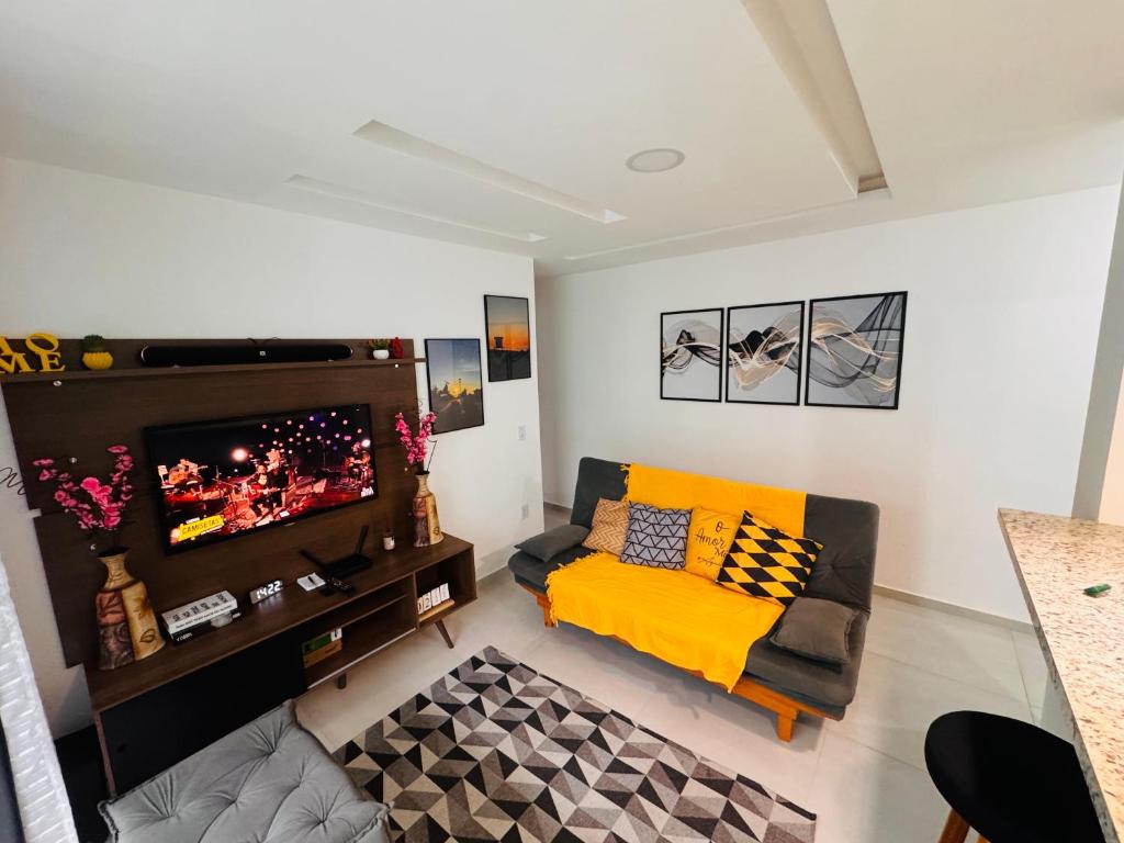 een woonkamer met een bank en een flatscreen-tv bij Ap 800m da praia in Rio das Ostras