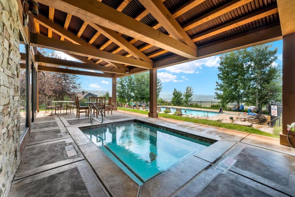 an outdoor pool with a wooden roof and a patio at Trappers Ridge Powder Haven in Eden