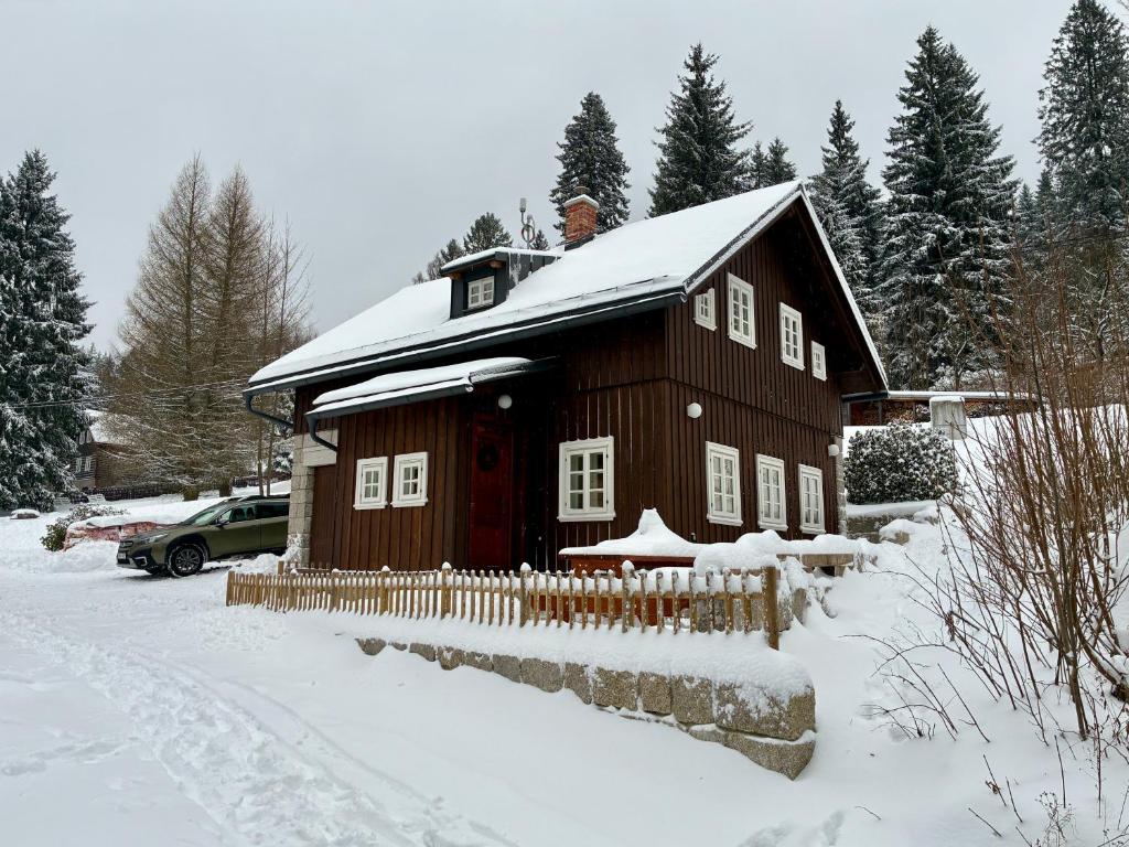 a wooden house in the snow with a fence at Chalupa Andělka in Josefŭv Dŭl