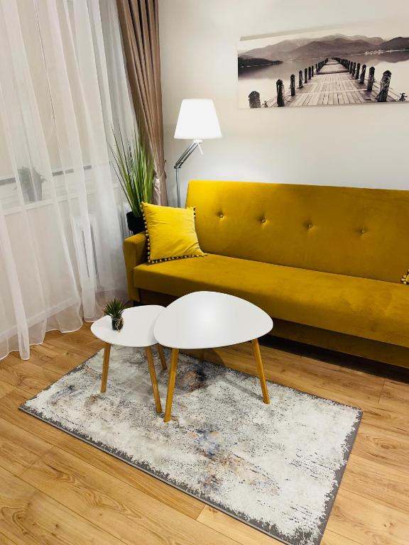 ein Wohnzimmer mit einem gelben Sofa und einem weißen Tisch in der Unterkunft Apartament Toruń Orbita bezpłatny parking in Toruń