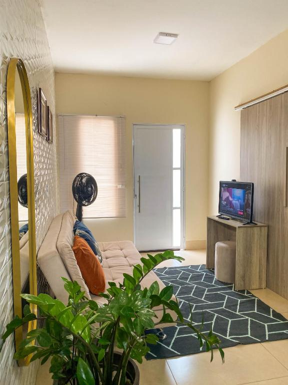 a living room with a couch and a tv at Flat Morada da Neblina! in Chapada dos Guimarães