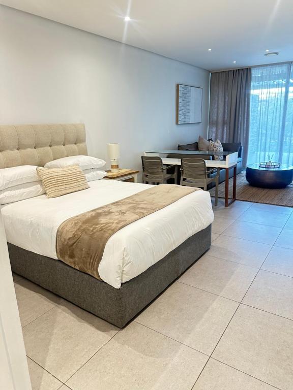 a bedroom with a large bed and a dining room at Pebble Beach Sibaya 146 in Sibaya