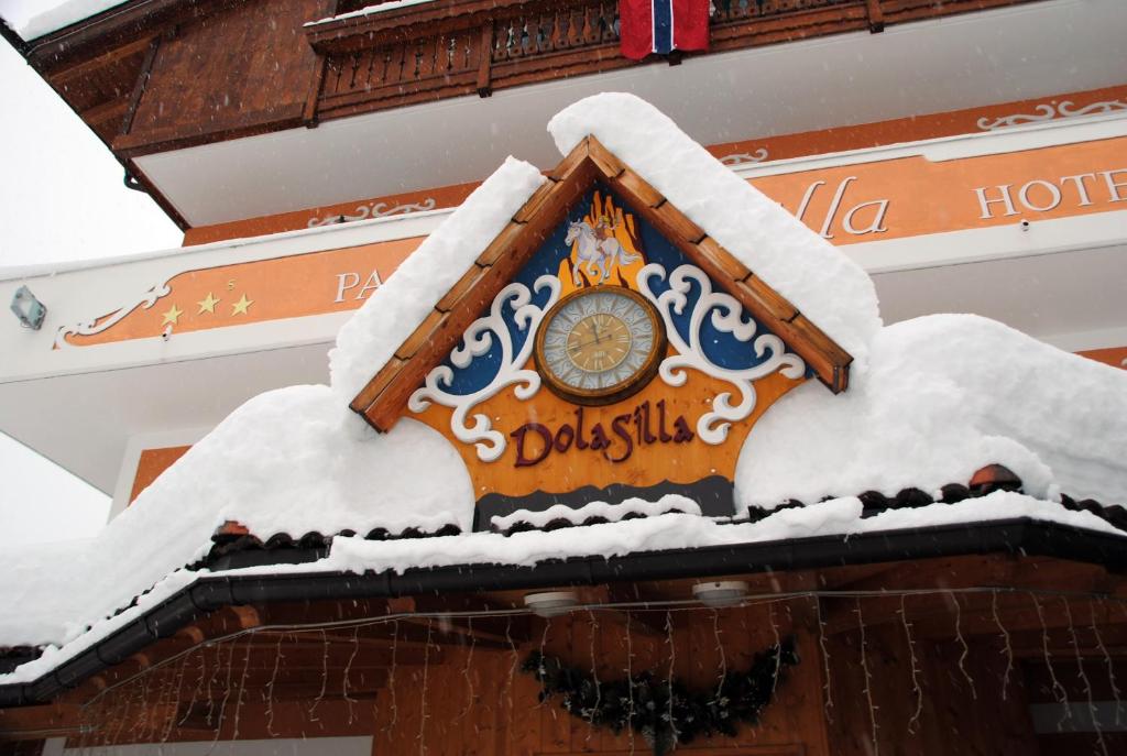 um relógio na lateral de um edifício coberto de neve em Dolasilla Park Hotel em Vigo di Fassa