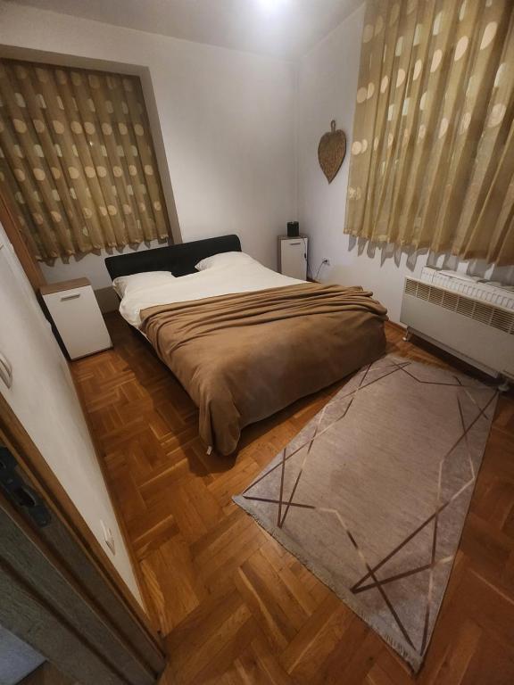 a bedroom with a large bed in a room with wooden floors at Vaikiki Apartman LM in Novi Pazar
