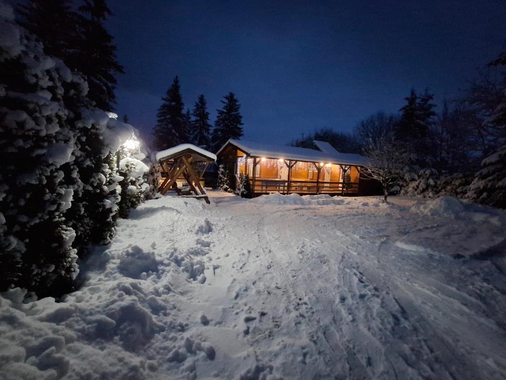 una cabina nella neve di notte con luci di Ezüst fenyő vendégház a Borzont