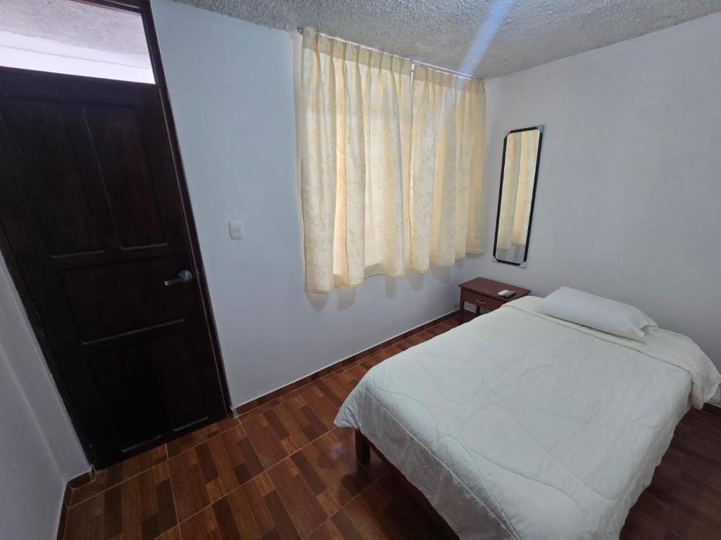 een slaapkamer met een wit bed en een raam bij Casa Wavve in Huanchaco