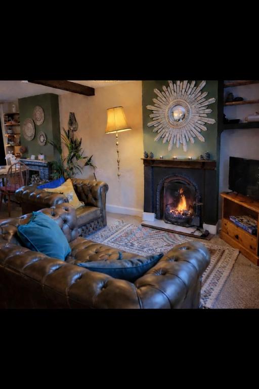 a living room with a leather couch and a fireplace at Evas cottage near Scafell in Gosforth