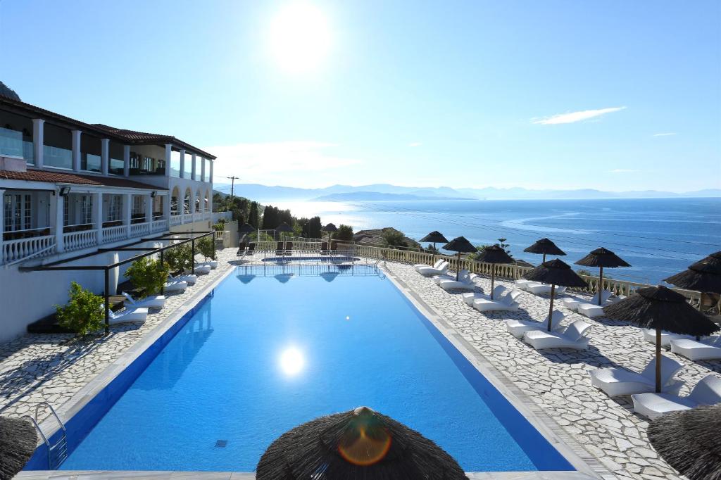 a swimming pool with umbrellas and the ocean at Pantokrator Hotel in Barbati