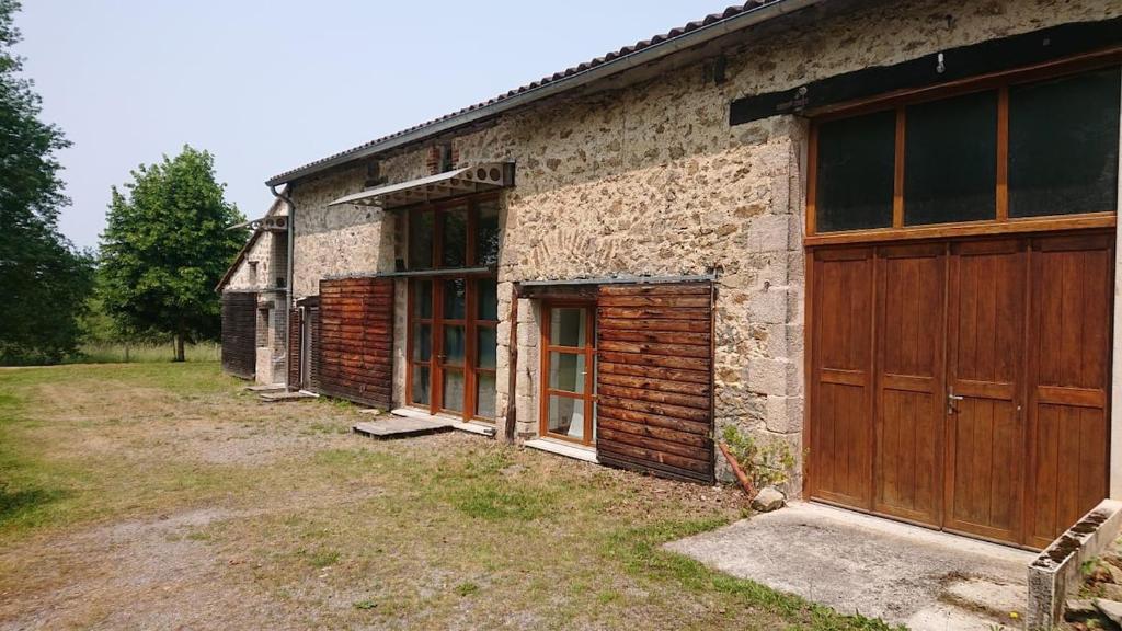 an old brick building with wooden doors on it at Maison familiale in Vars