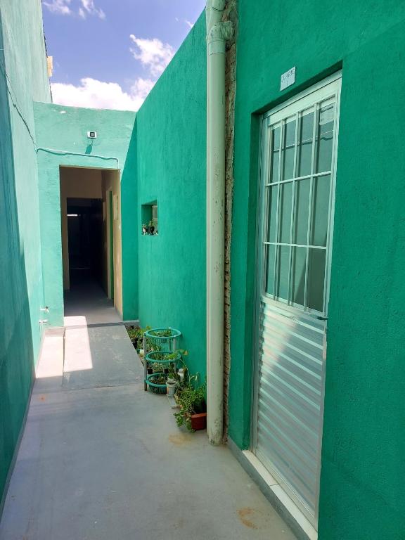 a green building with a garage door and a hallway at Seis Quarto Hospedaria - Suíte Com Ar ou Ventilador - Self Checkin - Centro in Juazeiro do Norte