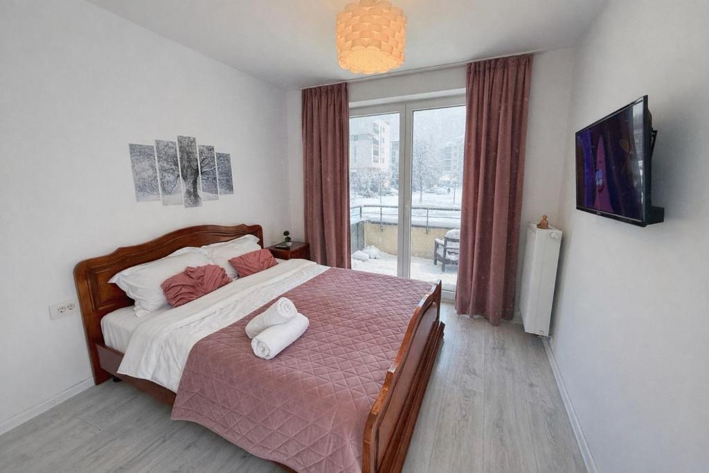 布拉索夫Plermont Luxury Apartments Coresi Kasper的一间卧室，里面有一张床和一扇大窗户。