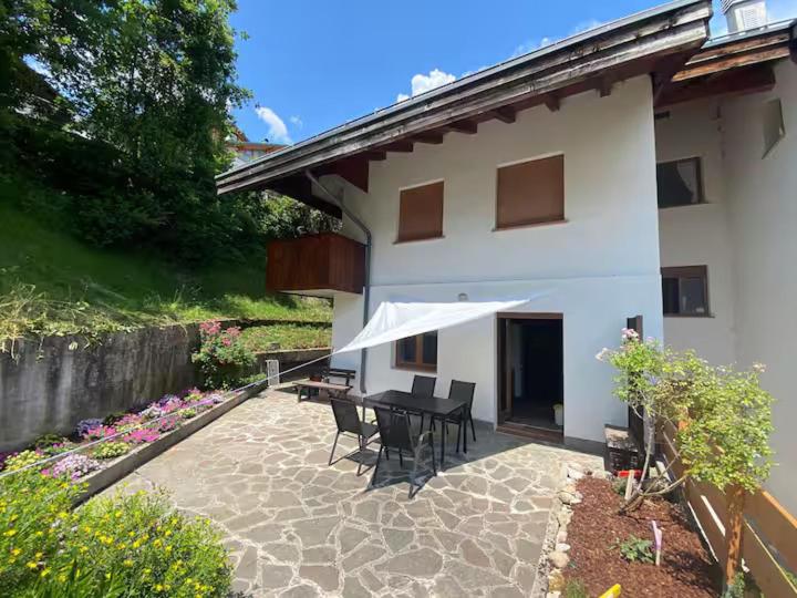 a patio with a table and chairs in front of a house at Terrazza Bloom in Pieve di Cadore