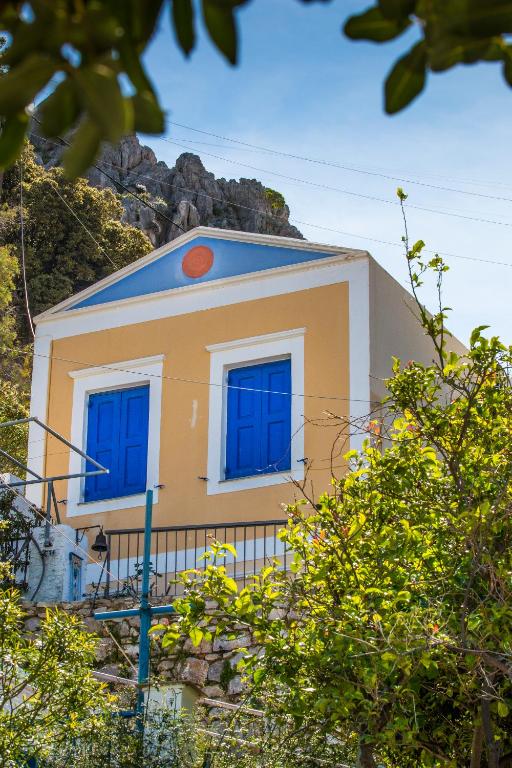 a house with blue windows on top of a hill at Symi Traditional Appartment in Symi