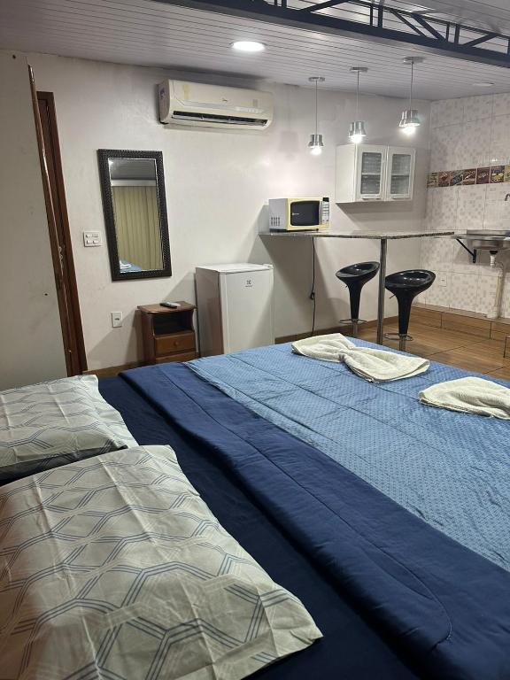 a bedroom with a blue bed and a kitchen at Hotel Araras in Manaus