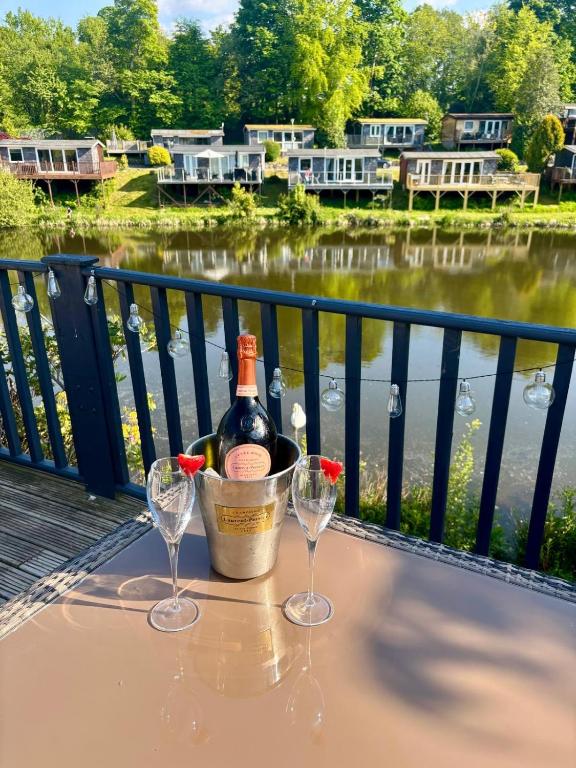 a bottle of wine sitting on a table with two glasses at Dillons Lakeside Lodge in Caeathro