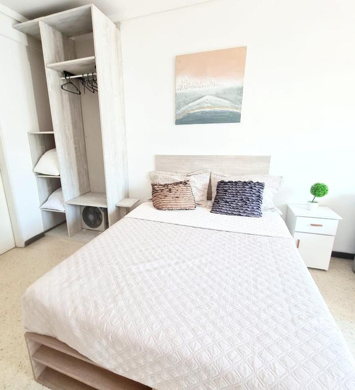 a white bedroom with a large bed with two pillows at Del Paseo al Mar in Mar del Plata