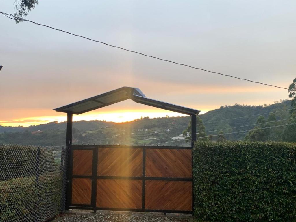 a wooden gate with a roof with a sunset in the background at El Edén in Guarne