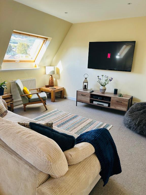a living room with a couch and a flat screen tv at Four Seasons B&B, Ground floor room, private bathroom, 3rd floor loft living area & self serve continental breakfast in Pitlochry
