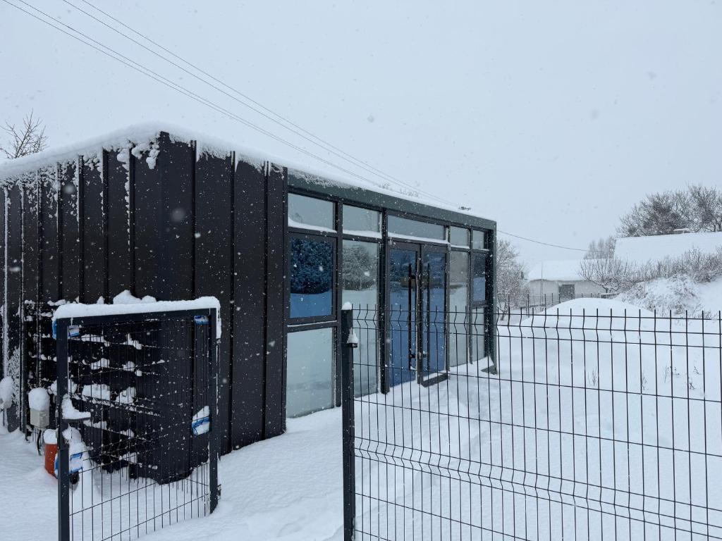 a glass building in the snow with a fence at Domki pod Kurzą Górą in Kurzętnik