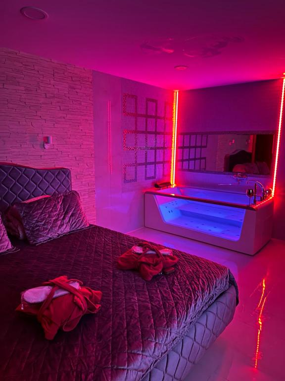 een slaapkamer met een bed en een bad met rode verlichting bij Jacuzzi studios 777 in Palanga