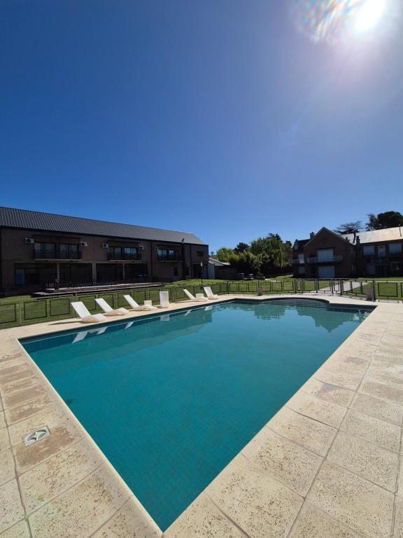 a large swimming pool with chairs and a building at Los Robles Apart Hotel in Sierra de la Ventana