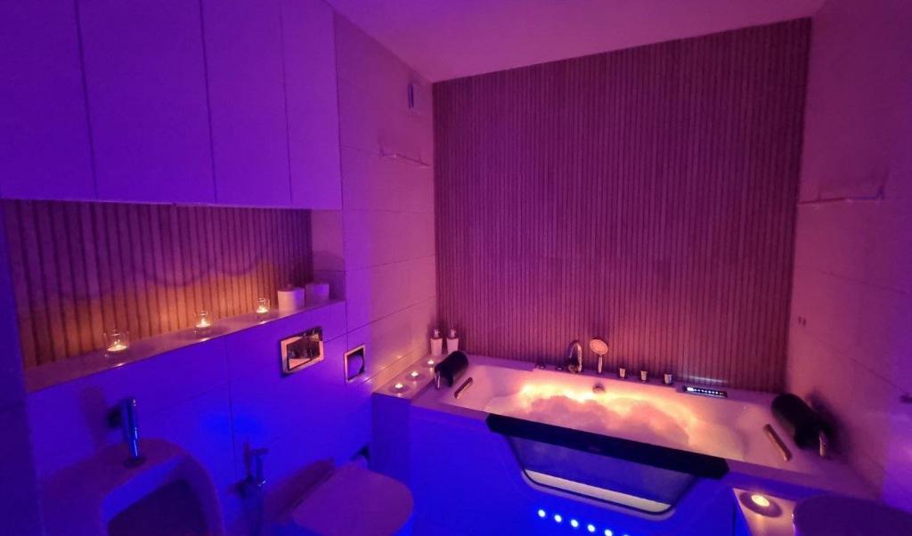 a bathroom with a tub and a toilet and purple lighting at Apartament Corner Cappuccino z wanną z hydromasażem w centrum Tomaszowa! Parliamo anche Italiano! in Tomaszów Mazowiecki