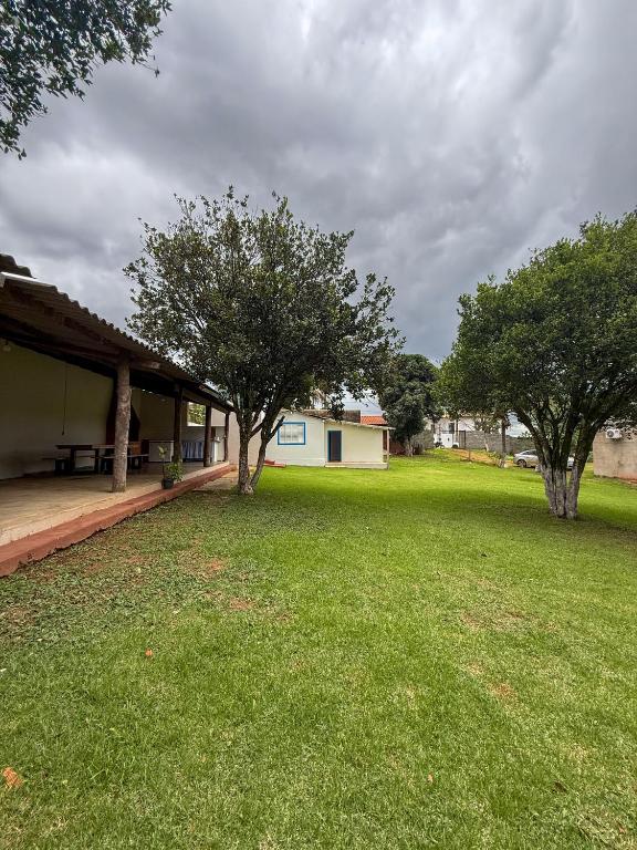 a yard with two trees and a house at Casa aconchegante e tranquila in Chapada dos Guimarães