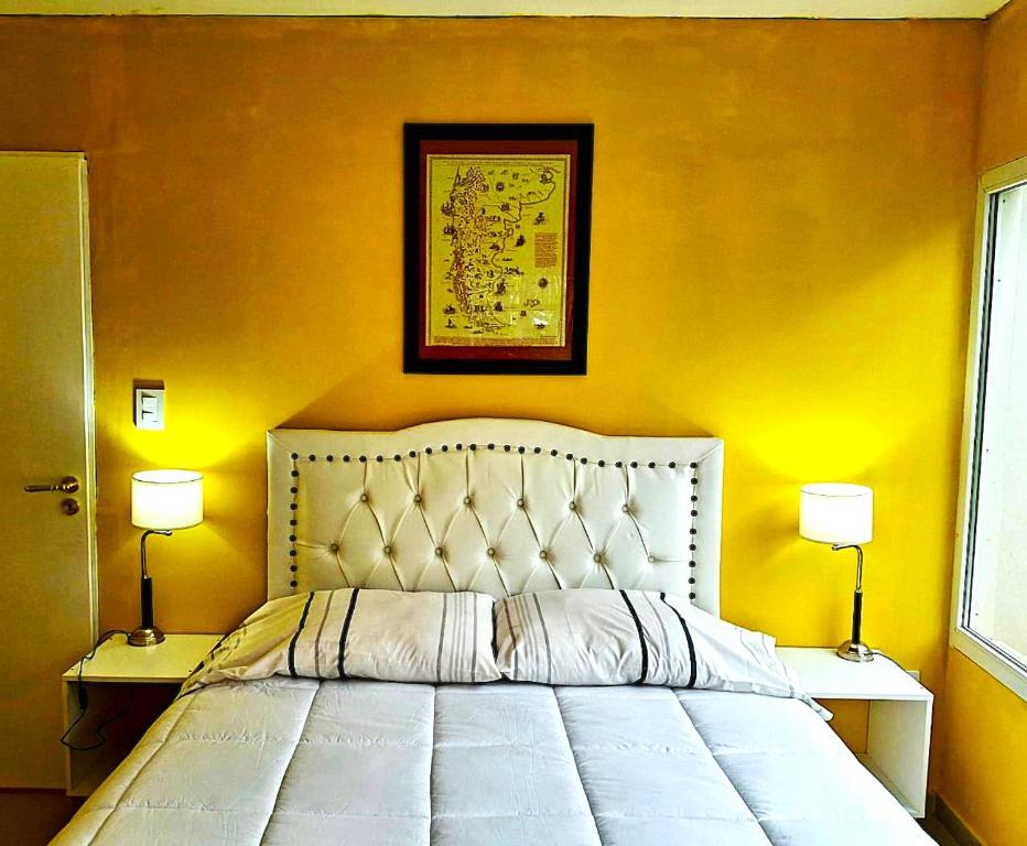 una camera da letto con un letto bianco con pareti gialle e due lampade di Familia Piatti B&B - Suites a Ushuaia