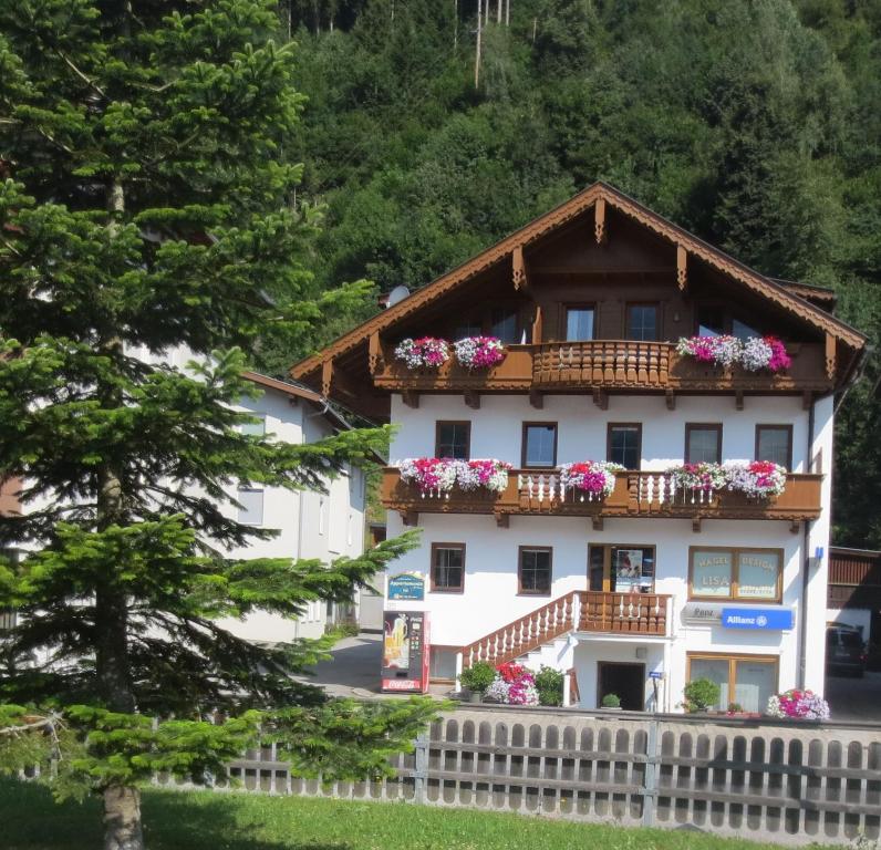 ein weißes Haus mit Blumen auf dem Balkon in der Unterkunft Apartments Penz in Zellberg