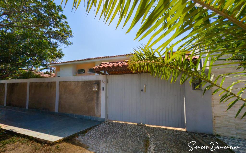 een huis met een hek en een garage bij Senses Dimension - Ipioca Beach Suites in Maceió