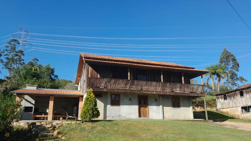 a house with a balcony on top of a yard at Casa Manarin in Água Boa