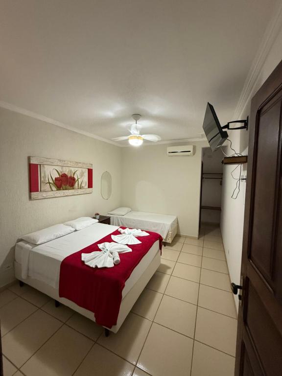 een hotelkamer met twee bedden en een televisie bij Pousada Marcondes in Paraty