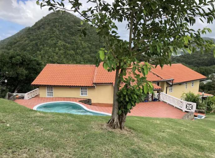 a house with a swimming pool next to a mountain at Uniek Villa in Gros Islet