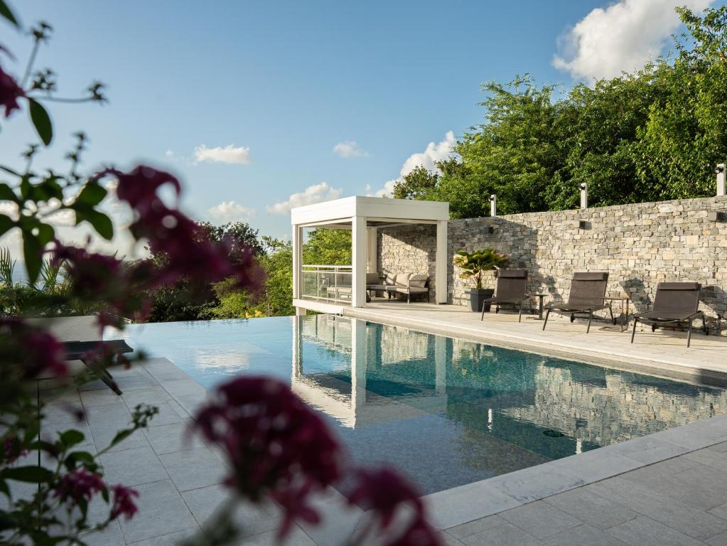 a swimming pool with a gazebo next to a stone wall at Bungalow Brise Marine - Plaisir d Évasion in Deshaies