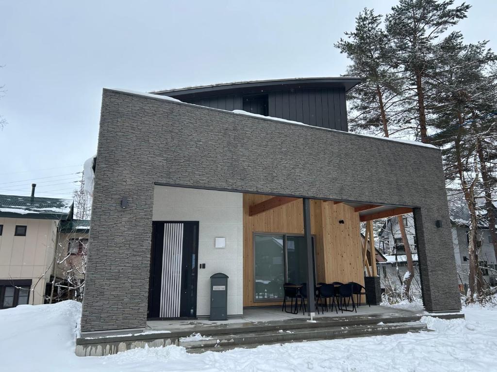 a house in the snow with tables and chairs at Hakuba Powder Cottage Eden in Hakuba
