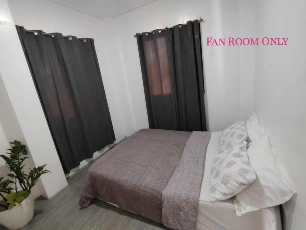 ein Schlafzimmer mit einem Bett und zwei schwarzen Vorhängen in der Unterkunft Yannas transient house in Roxas City
