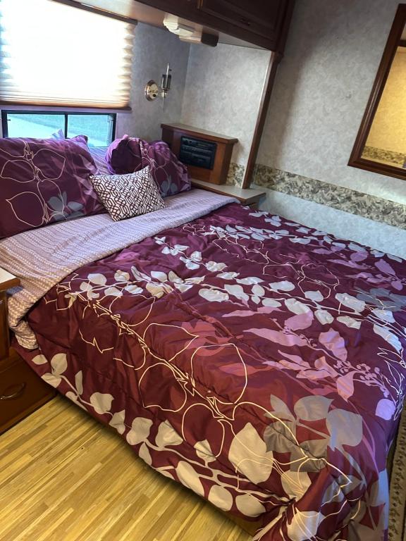 a bedroom with a large bed with a purple comforter at Comfortable and cozy RV in Lehigh Acres