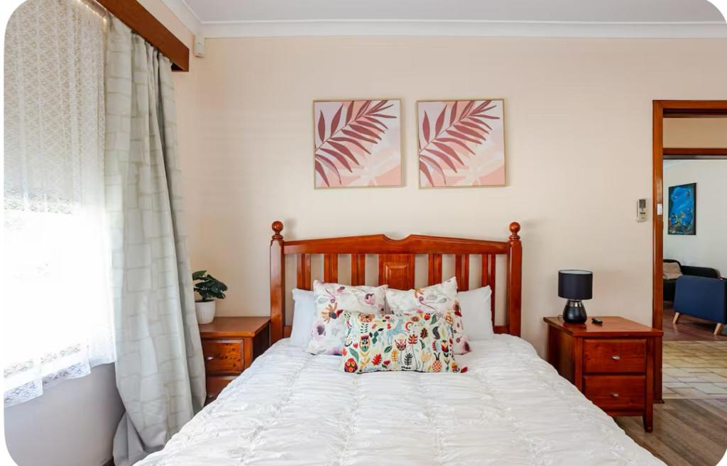 a bedroom with a large white bed with pillows at Holiday house in Roleystone