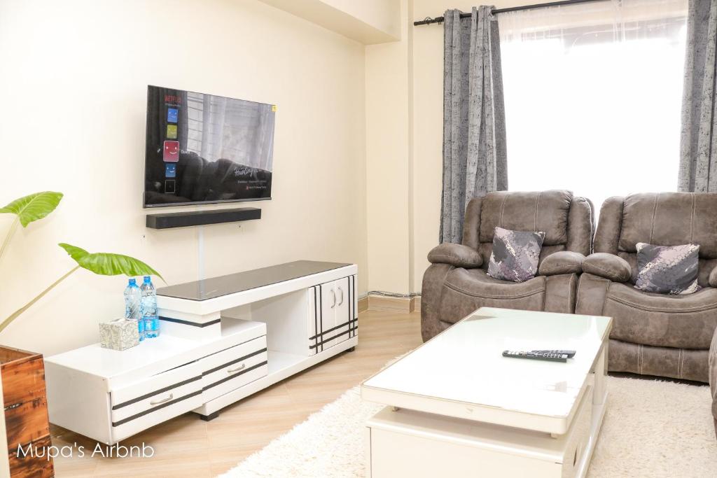 a living room with two chairs and a tv at Mupa Luxury Condo IV BnB in Nyahururu