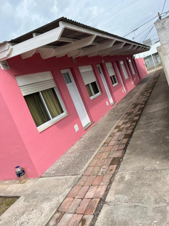 a pink house with a black roof at Departamentos Valquiria in Monte Hermoso