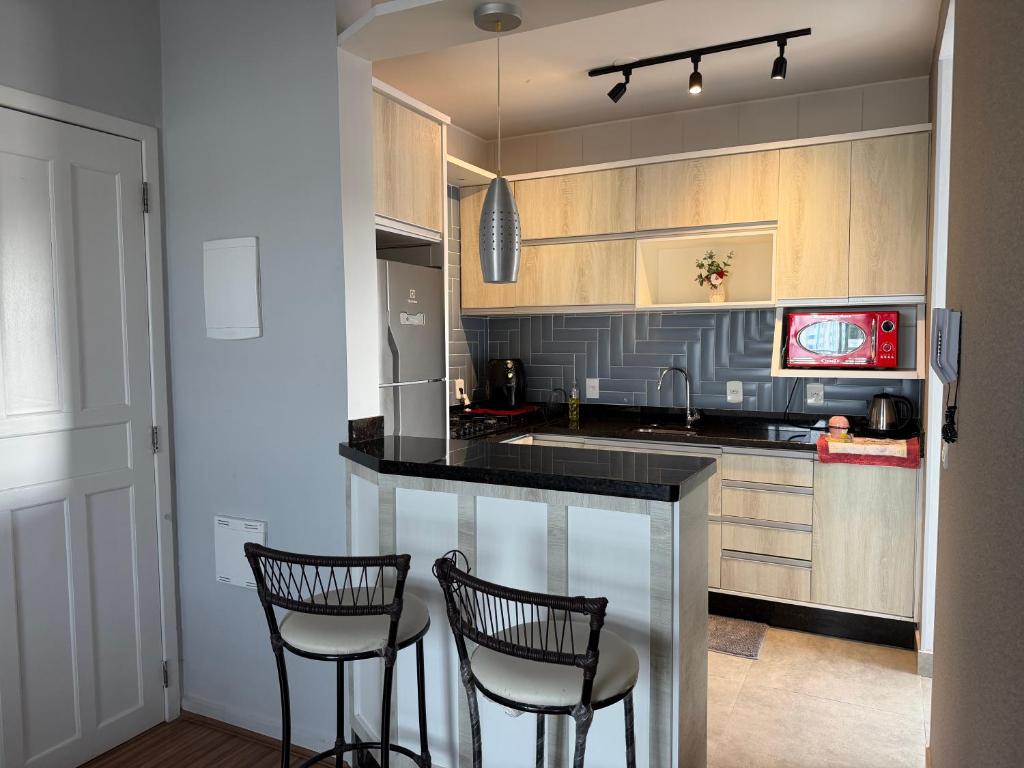 een keuken met 2 barkrukken en een aanrecht bij Lindo apartamento completo e com garagem coberta in Palhoça